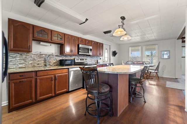 kitchen with dark hardwood / wood-style flooring, stainless steel appliances, sink, a center island, and hanging light fixtures