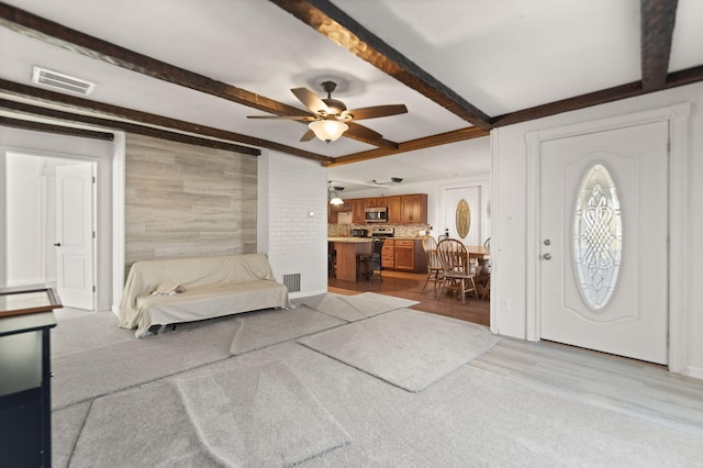 foyer entrance featuring beamed ceiling, ceiling fan, light hardwood / wood-style floors, and wood walls