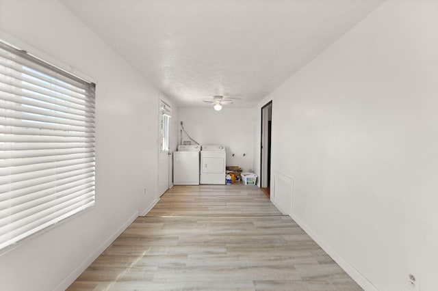 hallway featuring independent washer and dryer, light wood-type flooring, and a textured ceiling