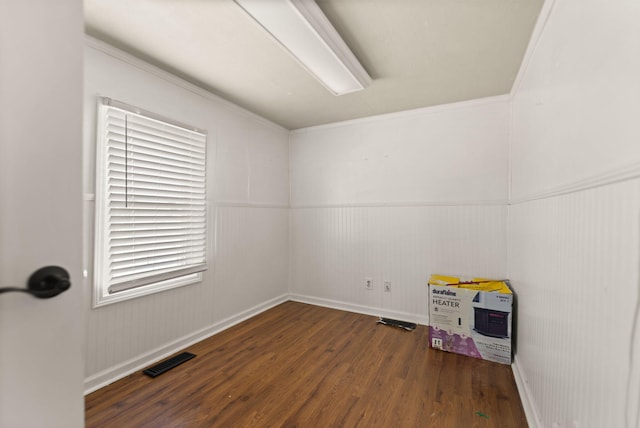 empty room featuring dark hardwood / wood-style floors, ornamental molding, and wood walls