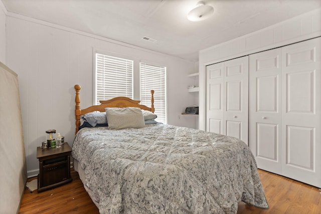 bedroom with hardwood / wood-style floors, ornamental molding, and a closet