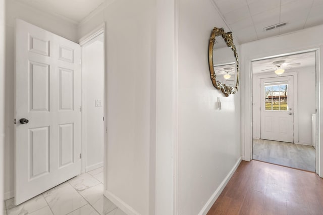 hall with ornamental molding and light hardwood / wood-style flooring