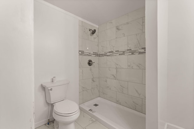 bathroom featuring a tile shower and toilet