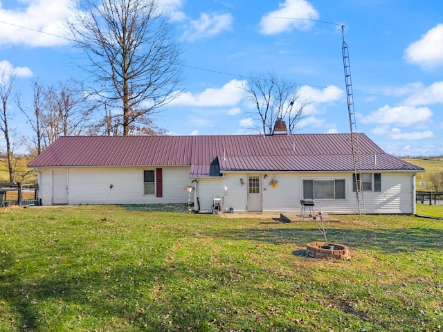 rear view of house with a lawn and an outdoor fire pit