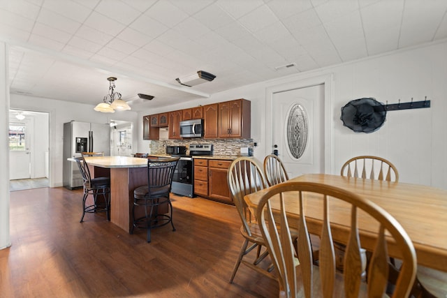 kitchen with hanging light fixtures, decorative backsplash, stainless steel appliances, and dark hardwood / wood-style floors