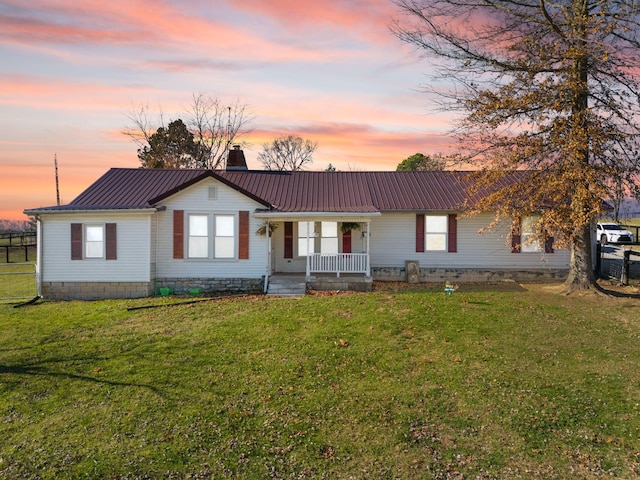 ranch-style home featuring covered porch and a yard