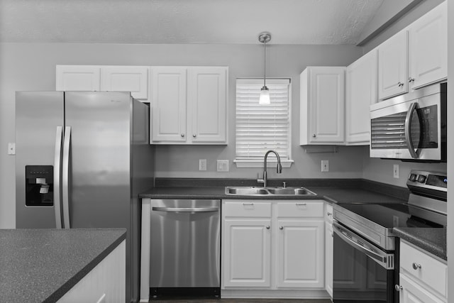 kitchen featuring appliances with stainless steel finishes, a textured ceiling, sink, white cabinets, and hanging light fixtures