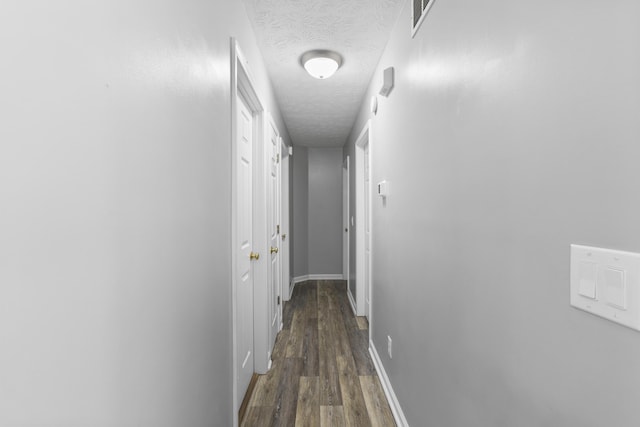 hallway with dark hardwood / wood-style flooring and a textured ceiling