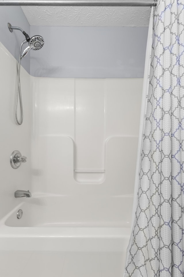 bathroom with a textured ceiling and shower / tub combo with curtain