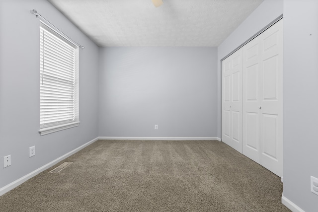 unfurnished bedroom with carpet flooring, multiple windows, a closet, and a textured ceiling