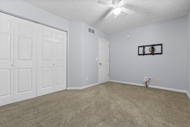 unfurnished bedroom with carpet, ceiling fan, a textured ceiling, and a closet