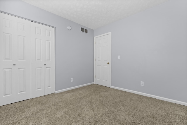 unfurnished bedroom with carpet, a textured ceiling, and a closet