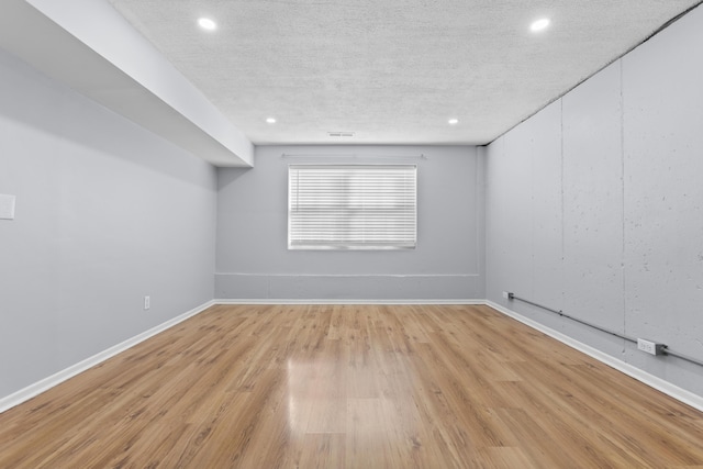 unfurnished room with light hardwood / wood-style flooring and a textured ceiling