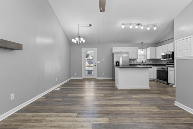 kitchen with appliances with stainless steel finishes, sink, white cabinets, hanging light fixtures, and lofted ceiling