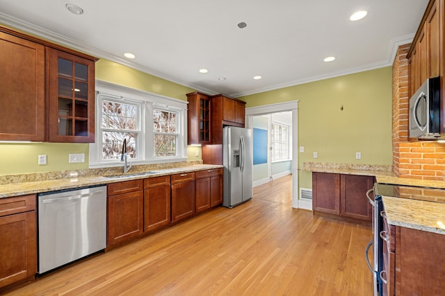 kitchen featuring sink, crown molding, light hardwood / wood-style flooring, stainless steel appliances, and light stone countertops