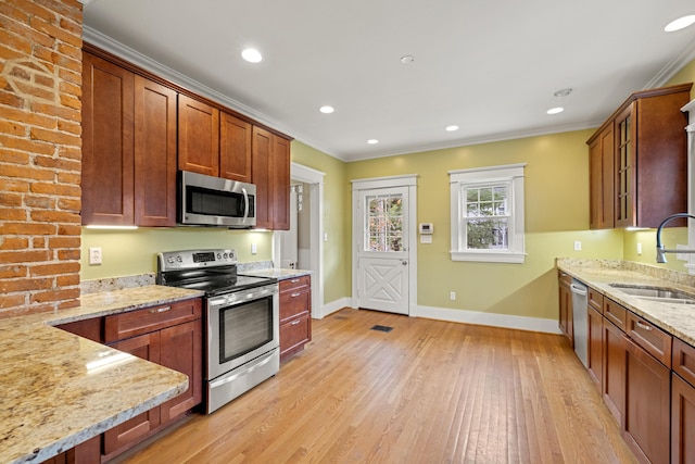 kitchen with light stone counters, stainless steel appliances, crown molding, and sink