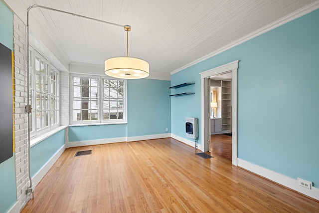 unfurnished dining area with hardwood / wood-style flooring, ornamental molding, heating unit, and a fireplace