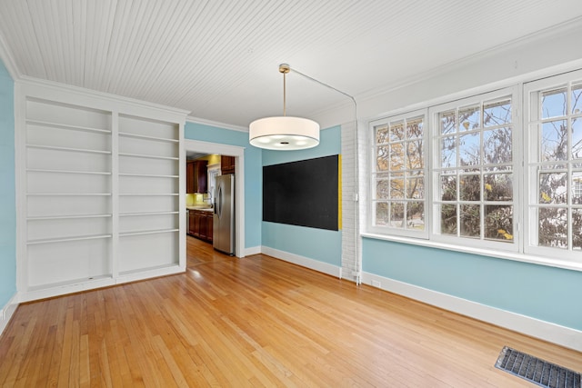 unfurnished dining area with built in shelves, crown molding, and hardwood / wood-style flooring