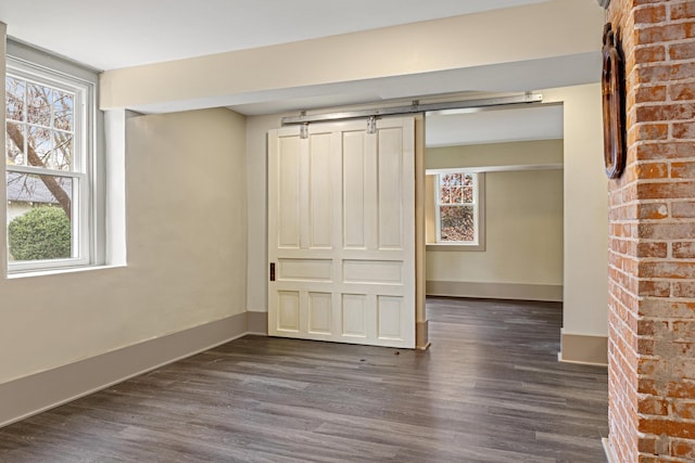 spare room featuring a barn door and dark hardwood / wood-style flooring