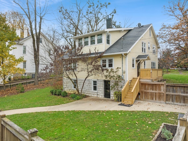 back of house featuring a lawn, a deck, and a patio area