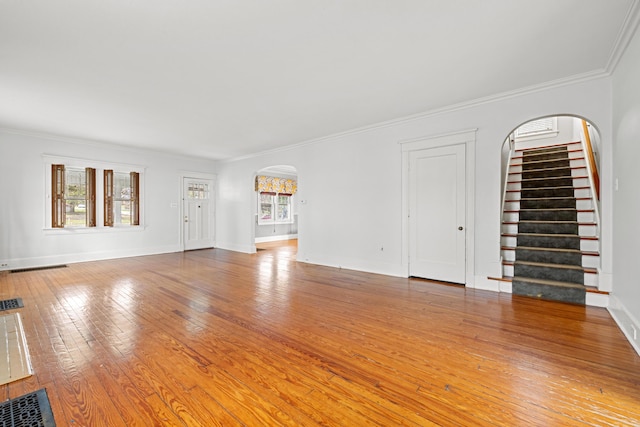 unfurnished living room featuring wood-type flooring and crown molding