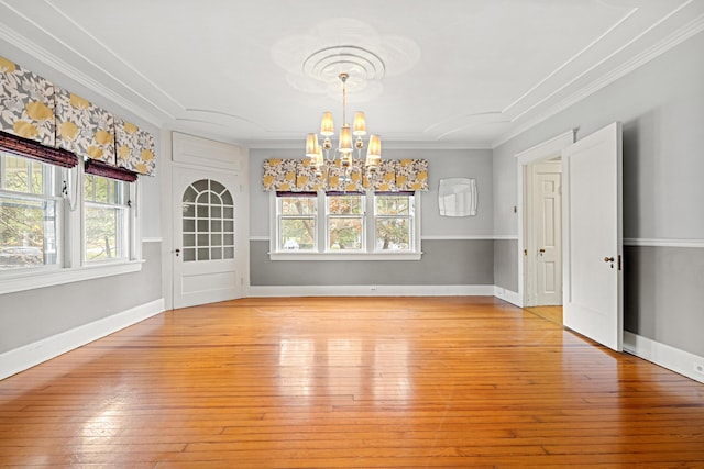 unfurnished dining area with an inviting chandelier, crown molding, and light hardwood / wood-style flooring