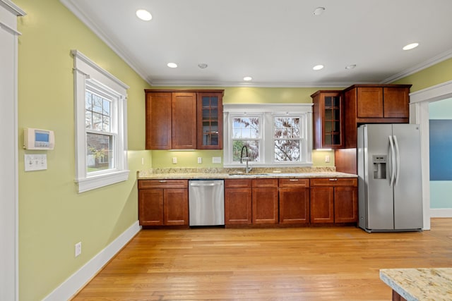 kitchen with sink, crown molding, light hardwood / wood-style flooring, stainless steel appliances, and light stone countertops