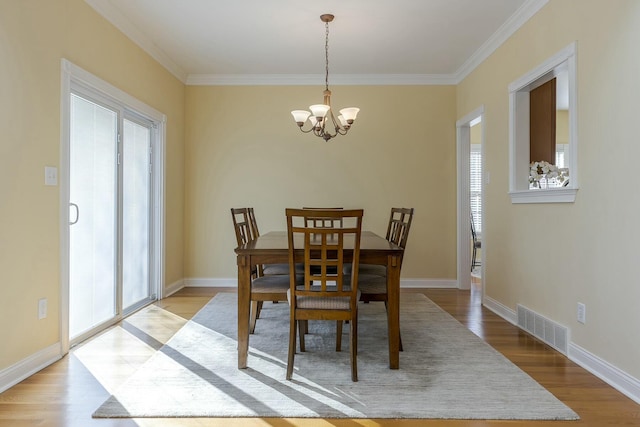 dining area featuring ornamental molding, a notable chandelier, and light wood-type flooring