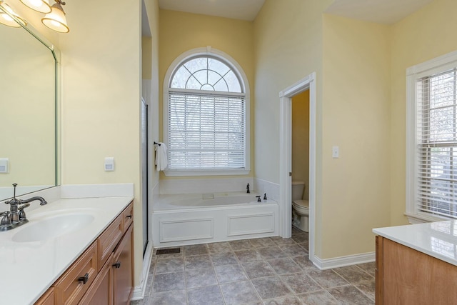 bathroom featuring tile patterned floors, vanity, toilet, and a tub to relax in