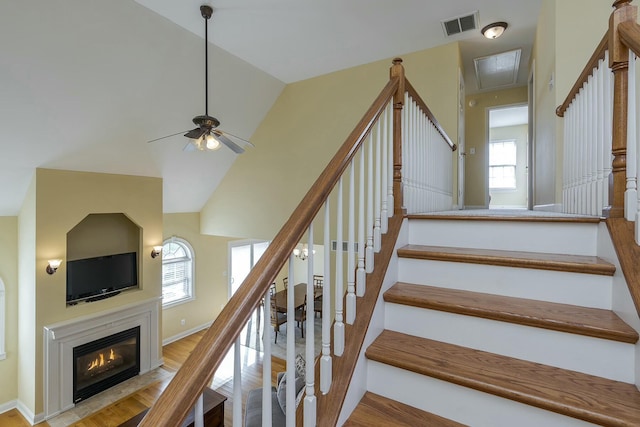 stairway with lofted ceiling, a healthy amount of sunlight, wood-type flooring, and ceiling fan