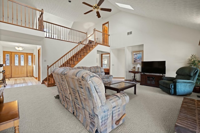 carpeted living room with a skylight, high vaulted ceiling, ceiling fan, and a healthy amount of sunlight