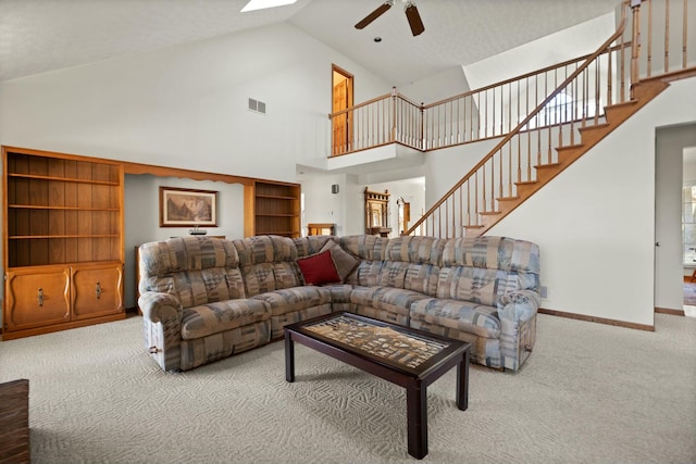 living room with carpet, ceiling fan, high vaulted ceiling, and a skylight