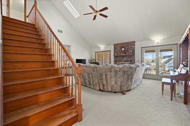 living room with carpet, a skylight, ceiling fan, high vaulted ceiling, and a fireplace