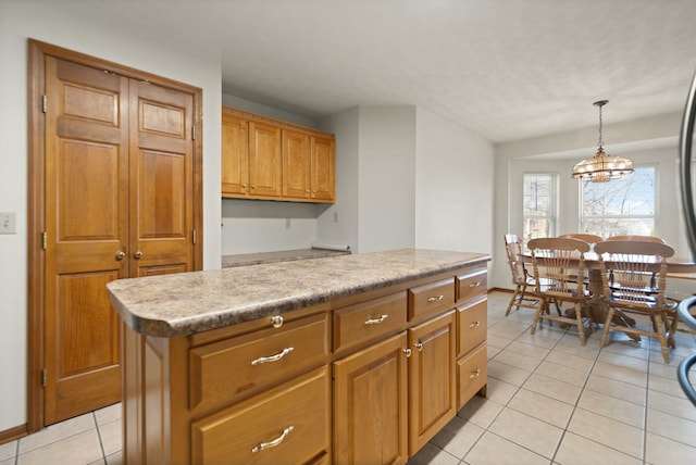 kitchen featuring pendant lighting, a kitchen island, light tile patterned flooring, and an inviting chandelier