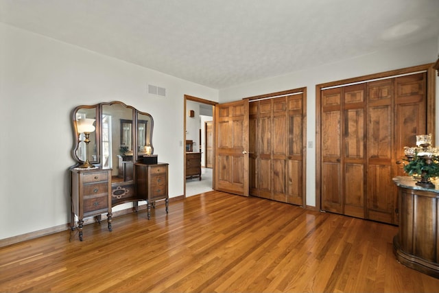 bedroom featuring wood-type flooring and multiple closets