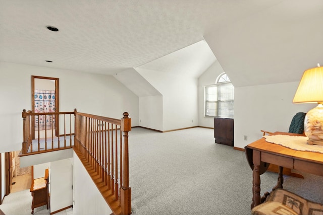 sitting room with a textured ceiling, light colored carpet, and lofted ceiling