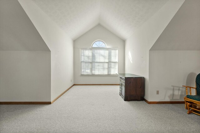 bonus room with a textured ceiling, light carpet, and vaulted ceiling