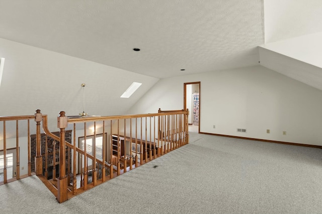 bonus room with carpet flooring, lofted ceiling with skylight, and a textured ceiling