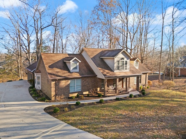 cape cod home featuring a porch and a front lawn