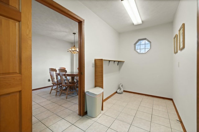 clothes washing area featuring light tile patterned floors, a textured ceiling, and a notable chandelier