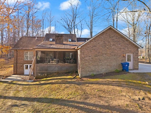 back of house featuring a lawn and a sunroom