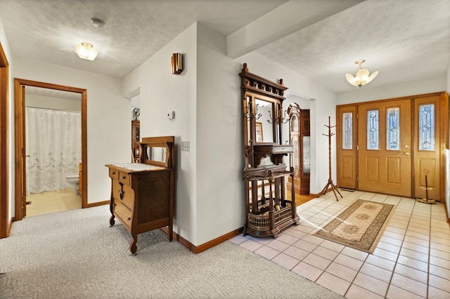 entryway with a textured ceiling, an inviting chandelier, and light tile patterned flooring