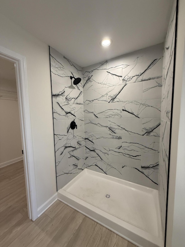 bathroom featuring wood-type flooring and a tile shower