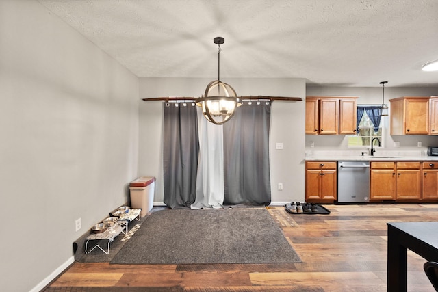 kitchen with pendant lighting, dishwasher, hardwood / wood-style flooring, a textured ceiling, and a notable chandelier