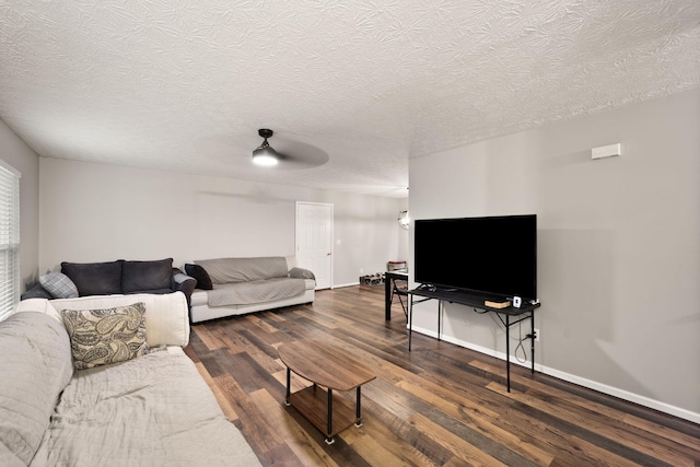 living room featuring ceiling fan, dark wood-type flooring, and a textured ceiling