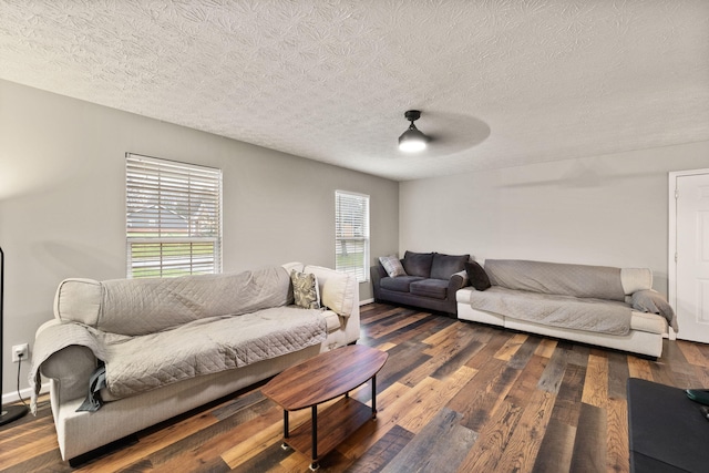 living room featuring a textured ceiling, ceiling fan, and dark wood-type flooring