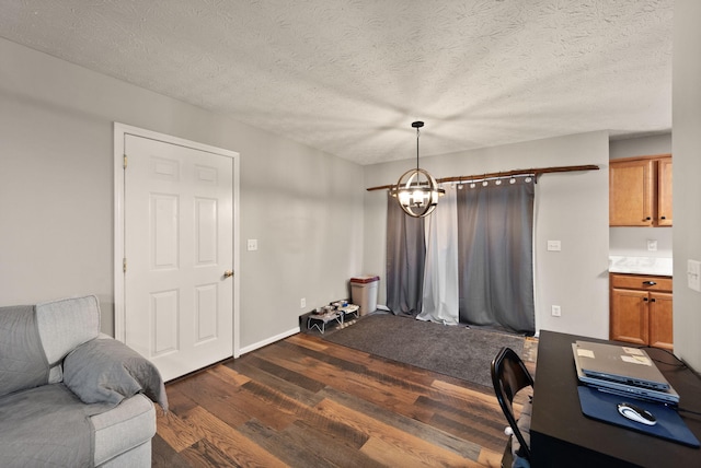 home office with a textured ceiling, a notable chandelier, and dark wood-type flooring