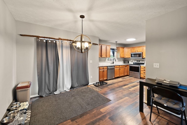 kitchen with a textured ceiling, stainless steel appliances, sink, dark hardwood / wood-style floors, and hanging light fixtures