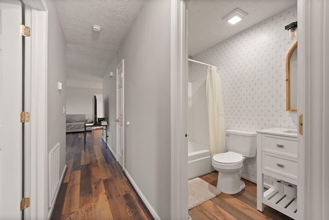 interior space featuring shower / bath combination with curtain, vanity, a textured ceiling, wood-type flooring, and toilet