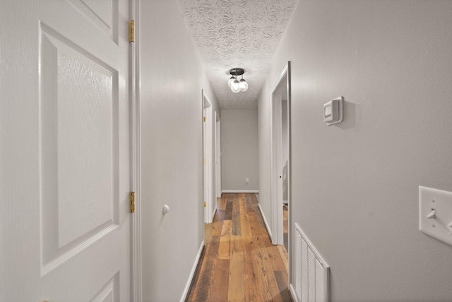 hall with hardwood / wood-style floors and a textured ceiling